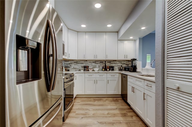 kitchen with sink, white cabinetry, light wood-type flooring, appliances with stainless steel finishes, and backsplash