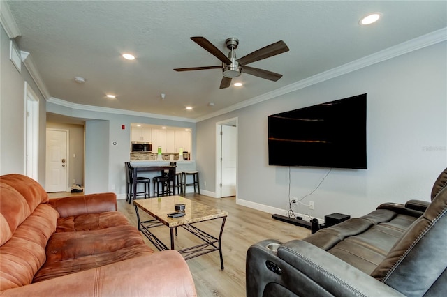 living room featuring ceiling fan, ornamental molding, and light hardwood / wood-style floors