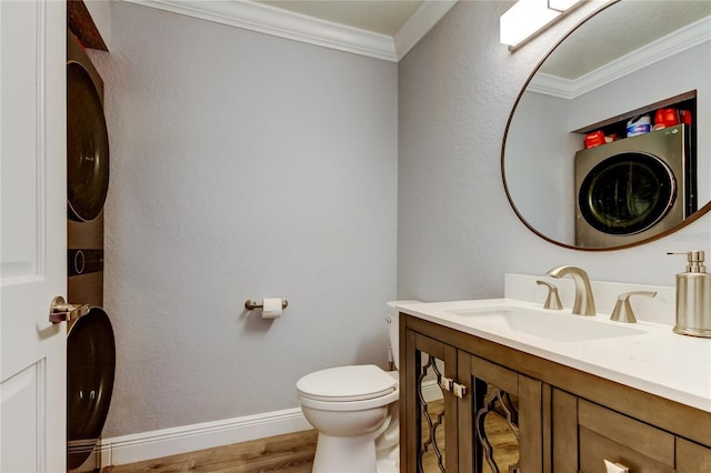 bathroom featuring stacked washer and dryer, toilet, crown molding, wood-type flooring, and vanity