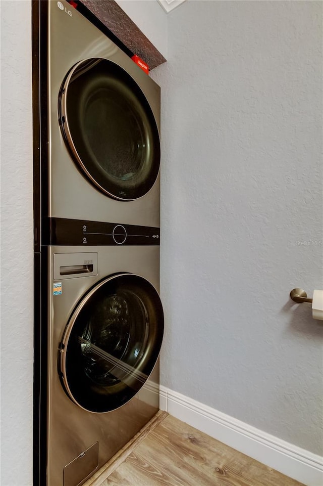 washroom with stacked washer / drying machine and wood-type flooring