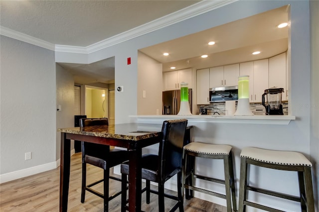 kitchen featuring crown molding, light hardwood / wood-style flooring, white cabinets, and appliances with stainless steel finishes