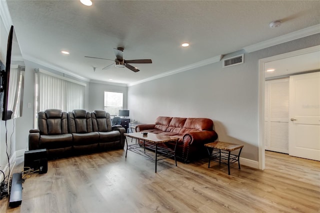 living room featuring ceiling fan, ornamental molding, a textured ceiling, and light wood-type flooring