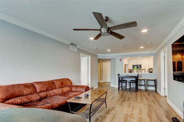 living room featuring ceiling fan, ornamental molding, light hardwood / wood-style flooring, and a textured ceiling