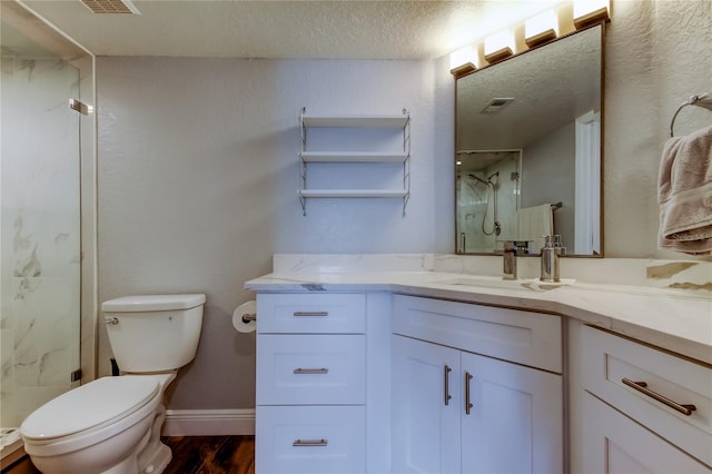 bathroom featuring vanity, toilet, a textured ceiling, and a shower with shower door