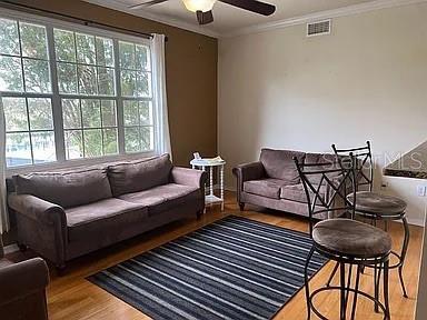 living room with hardwood / wood-style floors, ornamental molding, and ceiling fan