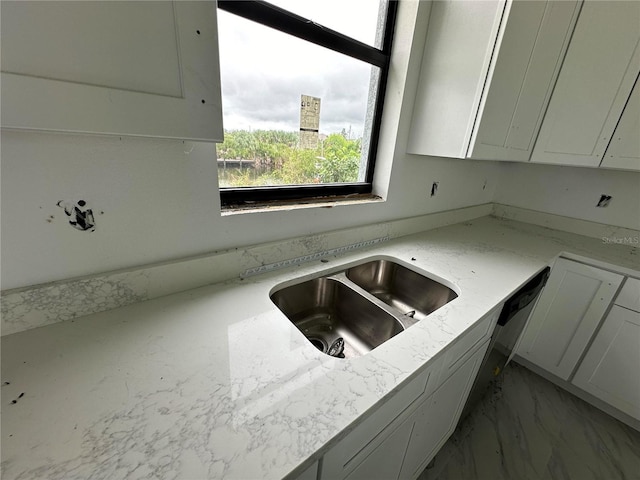 kitchen with light stone countertops, sink, and white cabinets