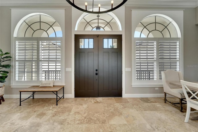 foyer with ornamental molding, plenty of natural light, and an inviting chandelier