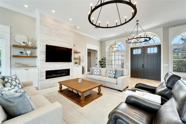 living room featuring a large fireplace, ornamental molding, and a notable chandelier