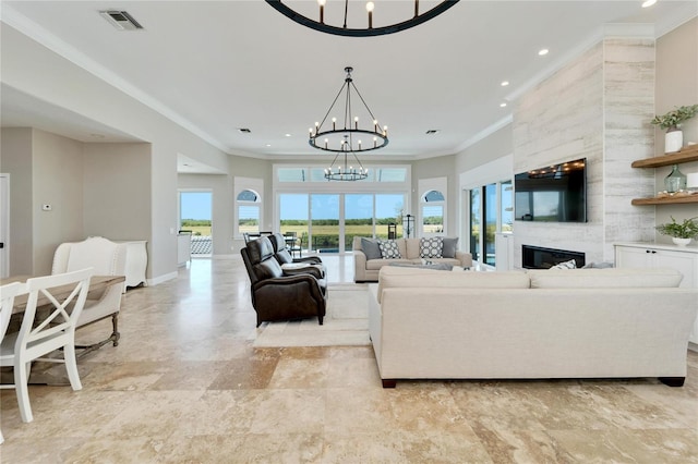 living room featuring a notable chandelier, plenty of natural light, ornamental molding, and a large fireplace