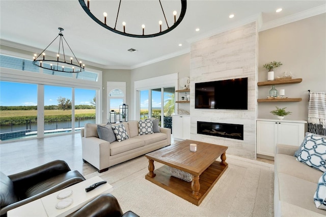 living room with a notable chandelier, crown molding, and a large fireplace