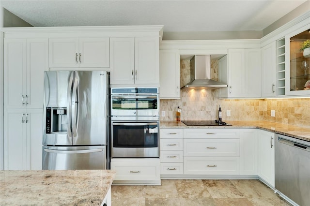 kitchen featuring stainless steel appliances, white cabinetry, wall chimney range hood, and backsplash