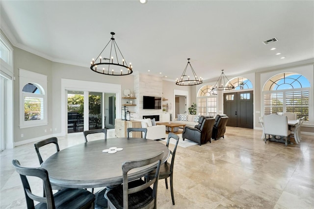 dining space with french doors, a large fireplace, crown molding, and a notable chandelier