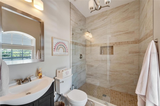 bathroom featuring tiled shower, vanity, toilet, and a chandelier