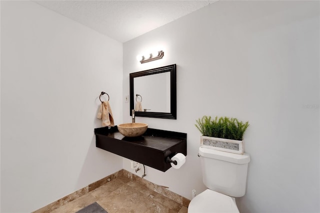 bathroom with sink, a textured ceiling, and toilet