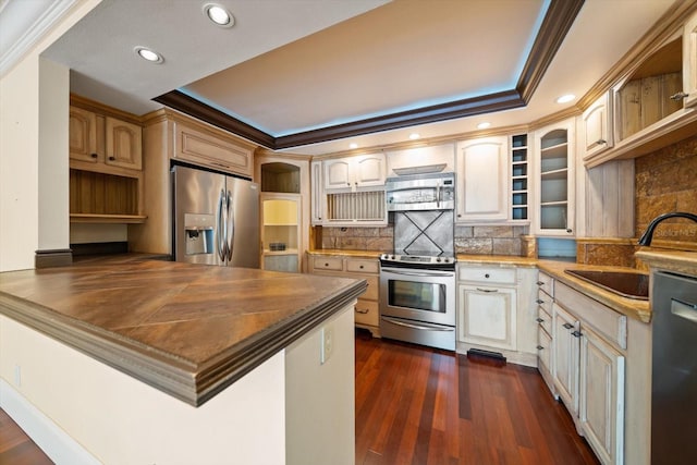 kitchen with sink, backsplash, dark hardwood / wood-style flooring, ornamental molding, and stainless steel appliances