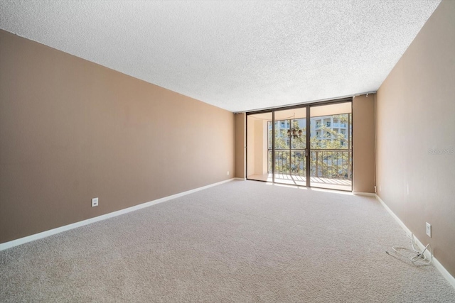 empty room with floor to ceiling windows, a textured ceiling, and carpet flooring