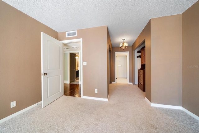 interior space featuring light colored carpet, a textured ceiling, and a chandelier