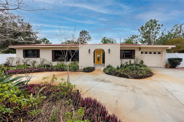 ranch-style home with concrete driveway, a tiled roof, an attached garage, and stucco siding