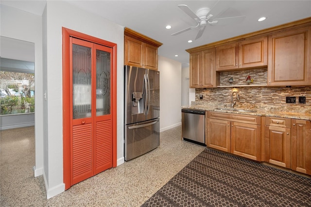 kitchen featuring appliances with stainless steel finishes, sink, backsplash, ceiling fan, and light stone counters