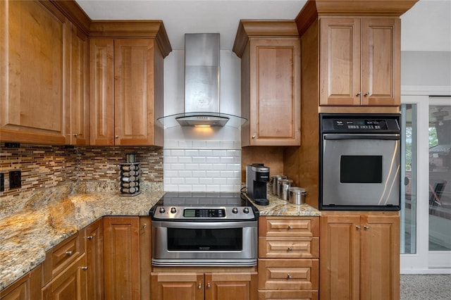 kitchen with wall chimney exhaust hood, appliances with stainless steel finishes, light stone countertops, and tasteful backsplash