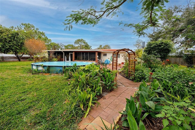 rear view of house with a fenced in pool, a yard, and a sunroom