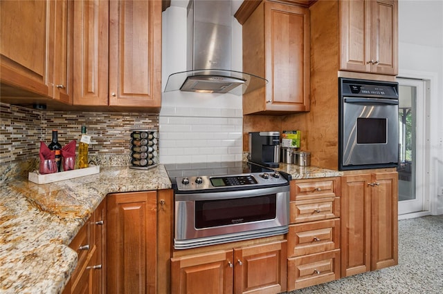 kitchen featuring backsplash, appliances with stainless steel finishes, brown cabinetry, light stone countertops, and wall chimney exhaust hood