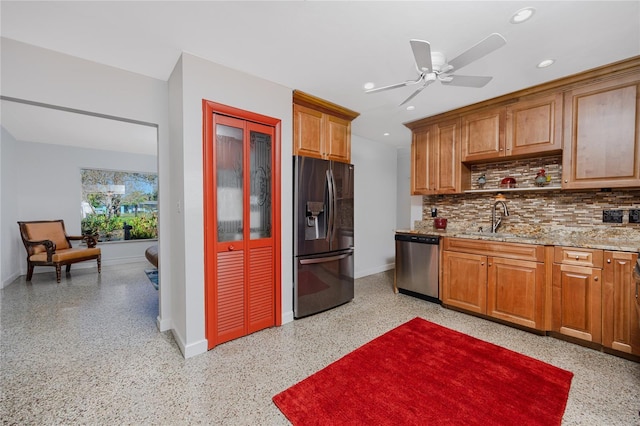 kitchen with light speckled floor, brown cabinets, decorative backsplash, appliances with stainless steel finishes, and a sink