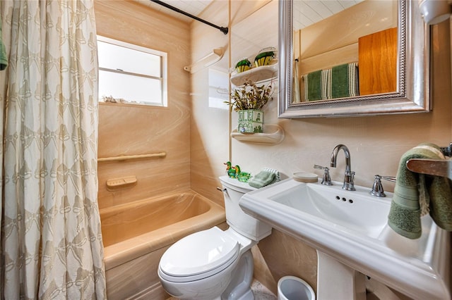 bathroom featuring a sink, shower / tub combo with curtain, and toilet