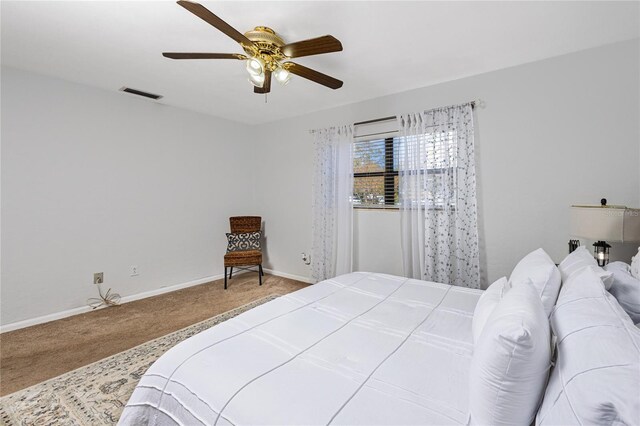 carpeted bedroom featuring a ceiling fan, visible vents, and baseboards