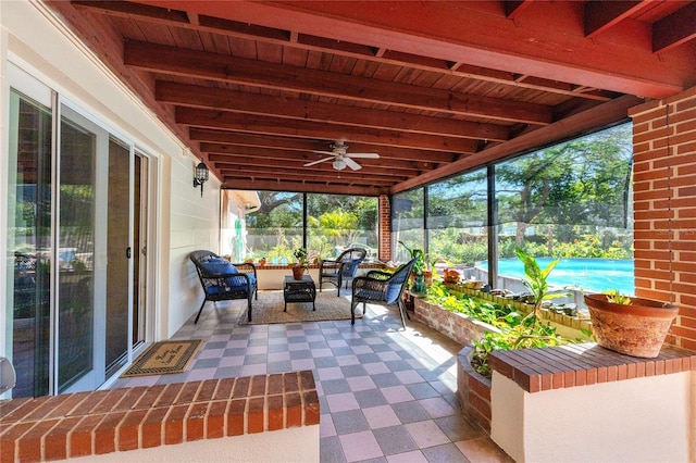 unfurnished sunroom featuring a healthy amount of sunlight, ceiling fan, wood ceiling, and beamed ceiling