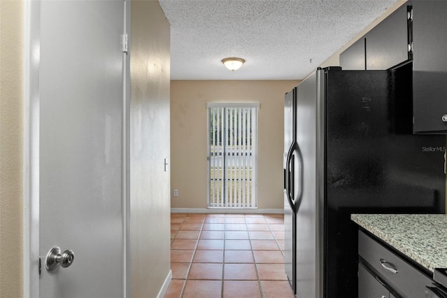 kitchen featuring light tile patterned floors, black fridge with ice dispenser, and a textured ceiling