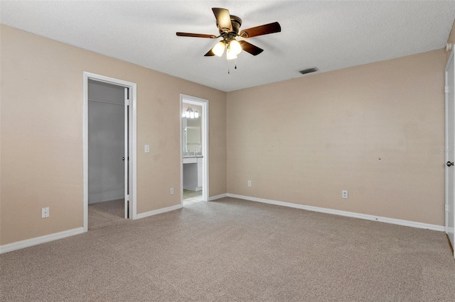 unfurnished bedroom with light carpet, connected bathroom, a walk in closet, and a closet