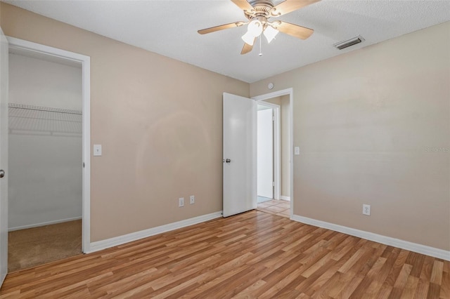 unfurnished bedroom featuring a closet, a walk in closet, and light hardwood / wood-style flooring