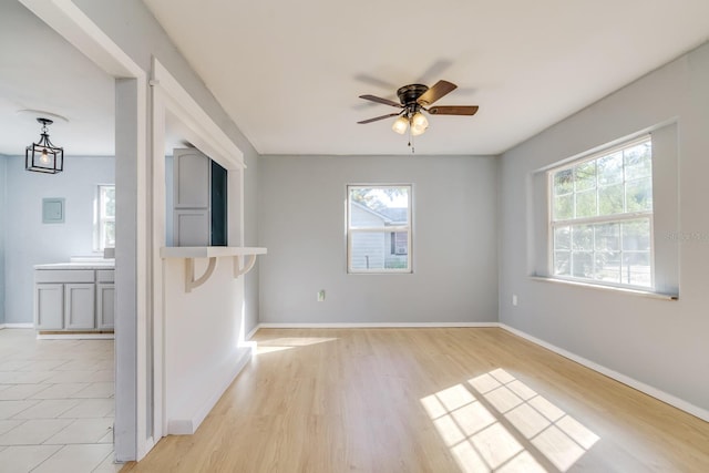 empty room featuring ceiling fan, plenty of natural light, and light wood-type flooring