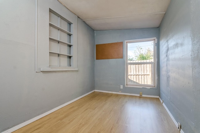 empty room featuring built in features and light hardwood / wood-style flooring