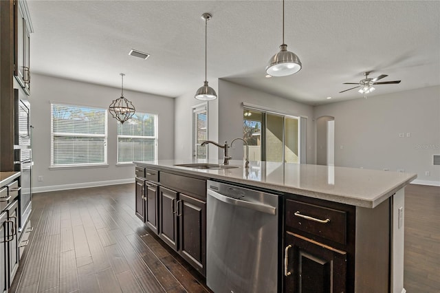 kitchen featuring dark brown cabinets, appliances with stainless steel finishes, dark hardwood / wood-style flooring, pendant lighting, and a kitchen island with sink