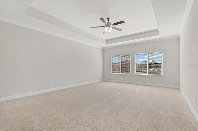 carpeted spare room featuring crown molding, ceiling fan, and a raised ceiling