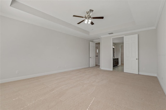 unfurnished bedroom with crown molding, a tray ceiling, light colored carpet, and ceiling fan