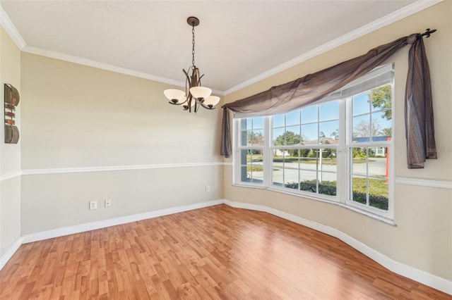 unfurnished room with a notable chandelier, crown molding, wood-type flooring, and a healthy amount of sunlight