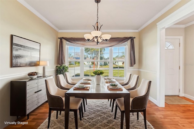 dining area featuring crown molding, wood-type flooring, and a chandelier