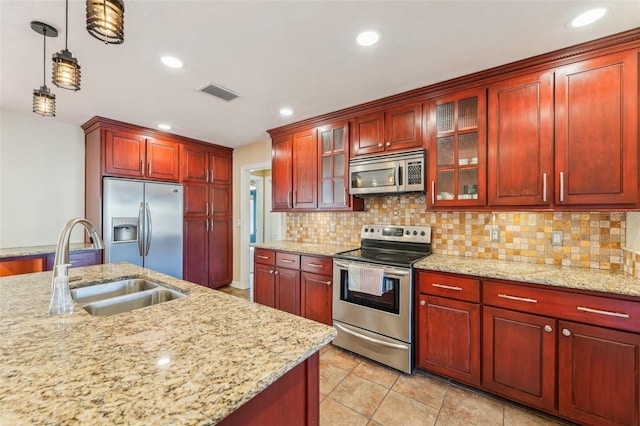 kitchen featuring tasteful backsplash, stainless steel appliances, light stone countertops, and hanging light fixtures