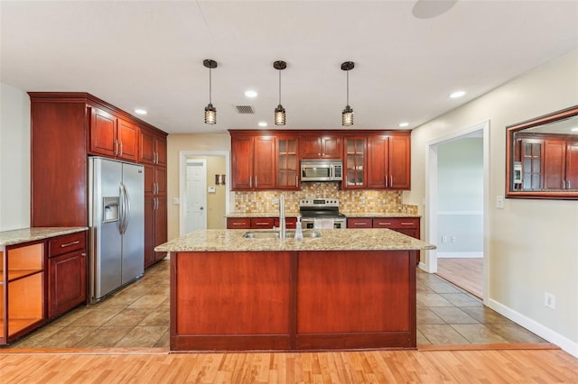 kitchen featuring sink, tasteful backsplash, decorative light fixtures, light hardwood / wood-style flooring, and stainless steel appliances