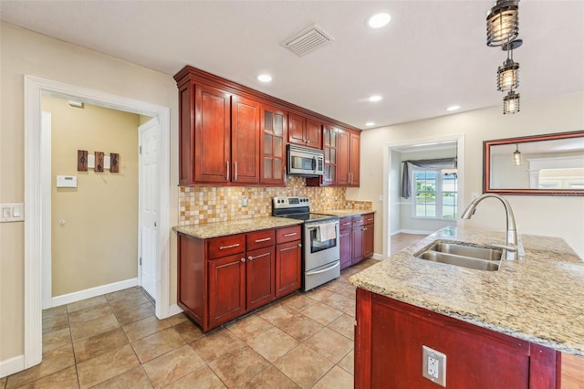 kitchen featuring appliances with stainless steel finishes, sink, decorative backsplash, hanging light fixtures, and light stone countertops