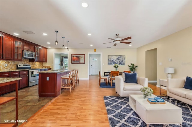 living room with sink, ceiling fan, and light wood-type flooring