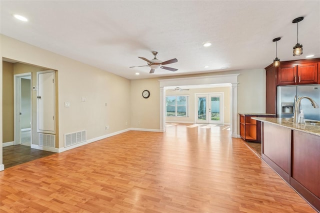 kitchen featuring decorative light fixtures, light hardwood / wood-style floors, stainless steel fridge with ice dispenser, light stone countertops, and french doors