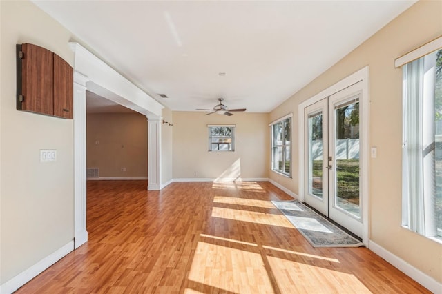 interior space with french doors, ceiling fan, decorative columns, and light hardwood / wood-style flooring