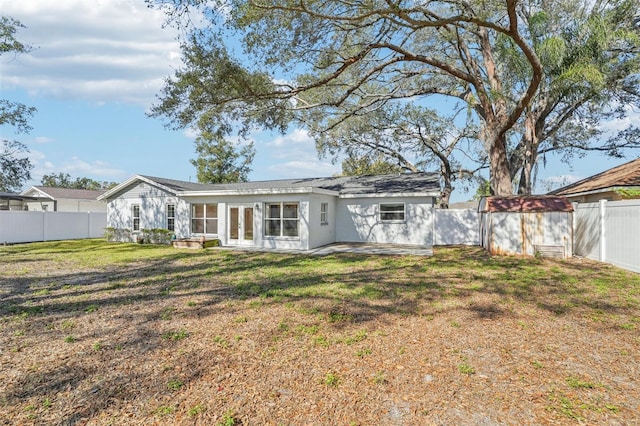 rear view of property with a storage unit and a lawn