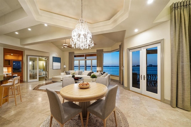 dining room featuring lofted ceiling, a water view, a notable chandelier, and french doors