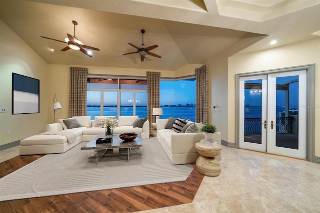 living room with a water view, vaulted ceiling, french doors, and light hardwood / wood-style flooring