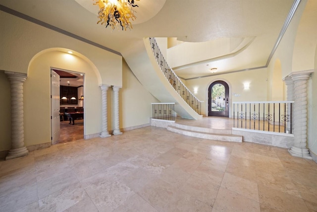 entryway featuring crown molding, a raised ceiling, and decorative columns